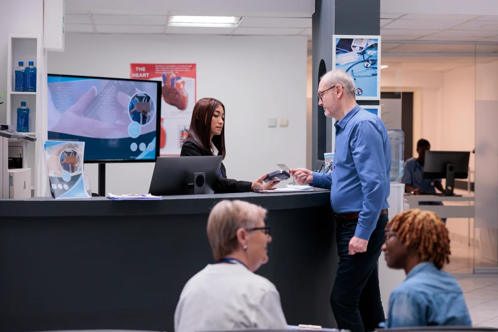people at a hospital reception desk waiting to be attended