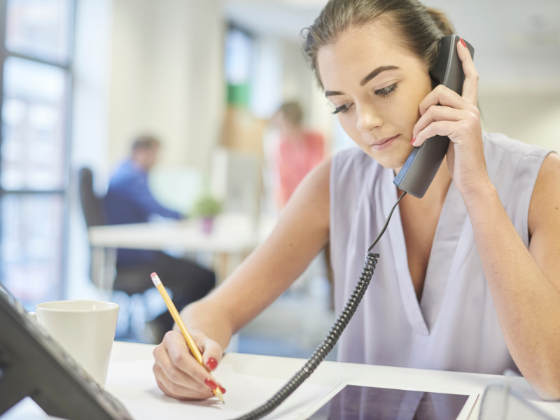 office woman taking notes while on a call